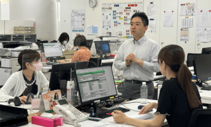 オフィスでスタッフ同士がコミュニケーションを取り、情報共有している様子